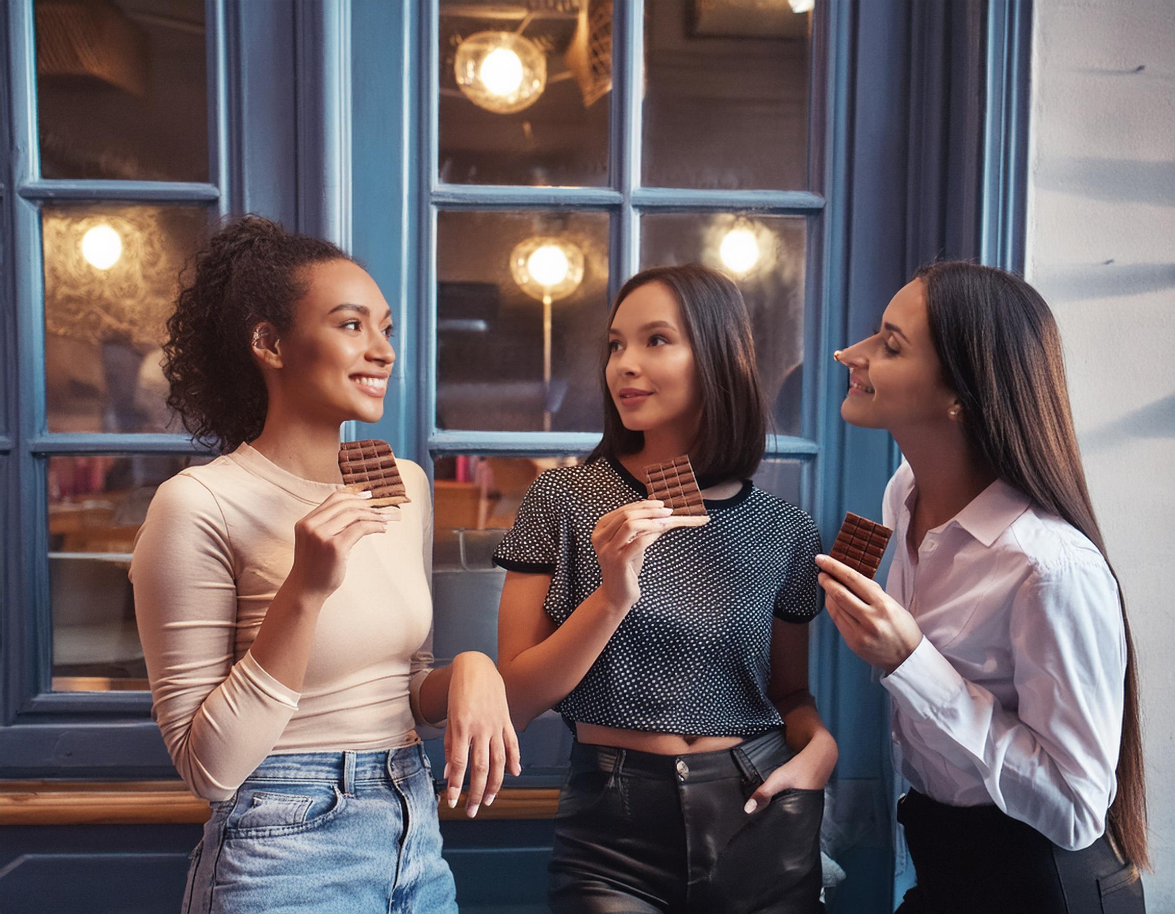groupe d'amis devant un magasin parlant et mangeant du chocolat